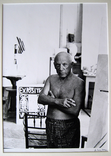 Cannes, 1957 (Picasso standing in white shorts in front of some canvases) by Andre Villers
